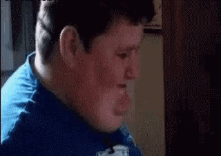 a close up of a man 's face with a blue shirt on making a funny face .