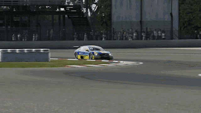 a blue and yellow race car is driving on a track with a sign that says ice cream in the background