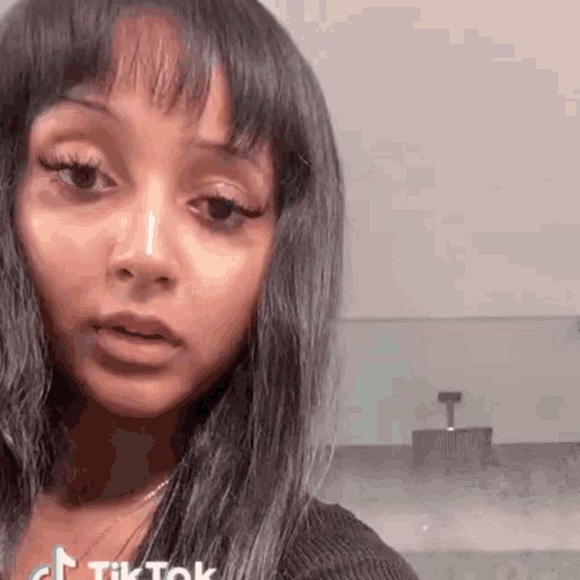 a close up of a woman 's face in a bathroom with a soap dispenser in the background .