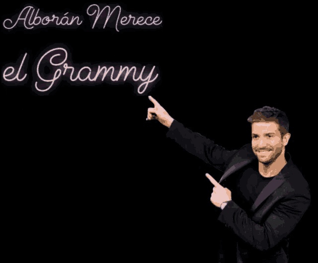 a man in a black suit points at the word grammy