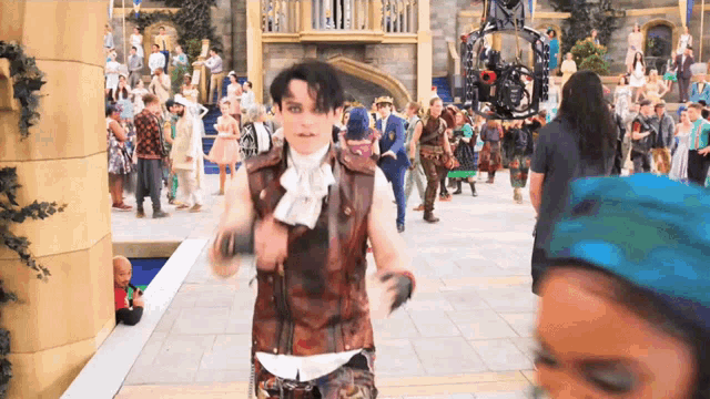 a man in a brown vest is walking in a crowded area