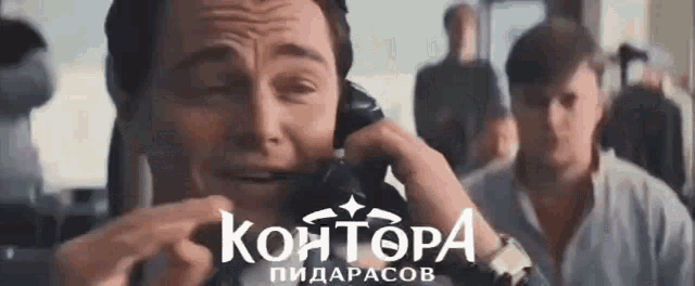 a man is crying while talking on a phone in front of a sign that says kantora