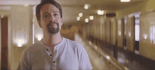 a man with a beard is standing in a hallway with a blurred background .