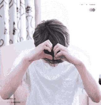a man is making a heart shape with his hands behind his head .