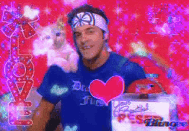 a man wearing a blue shirt with a heart on it holds a stuffed animal