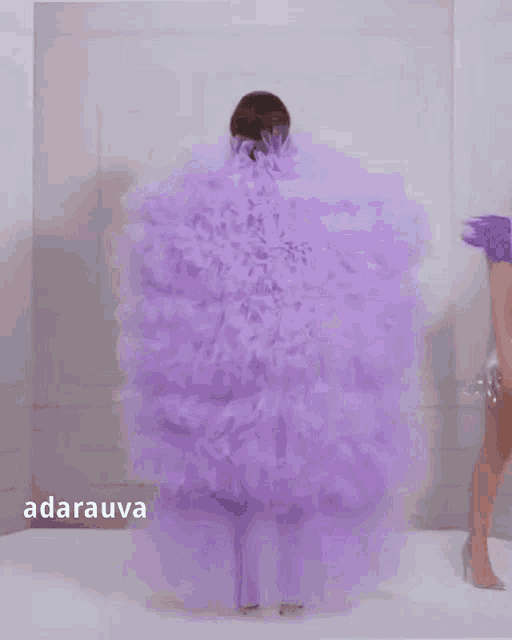 a woman in a purple dress is standing in front of a white wall with the word darauva on the bottom