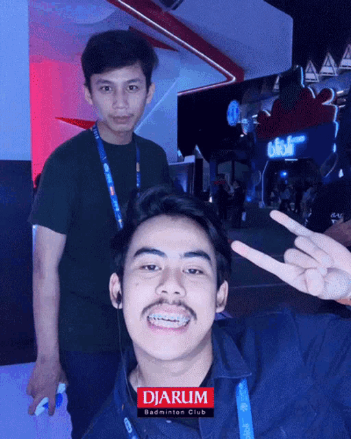 two men are posing for a picture and one of them is wearing a lanyard that says djarum badminton club