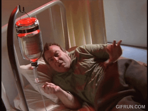 a man is laying in a hospital bed with a drip attached to his head