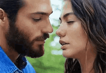 a man and a woman are kissing each other in a park .