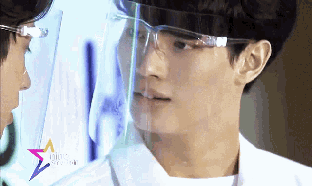 a man wearing a face shield and glasses is looking at another man