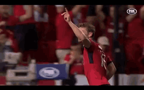 a soccer player is celebrating a goal in front of a crowd while wearing a number 1 jersey .