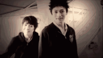 a black and white photo of two young men standing next to each other in a room .