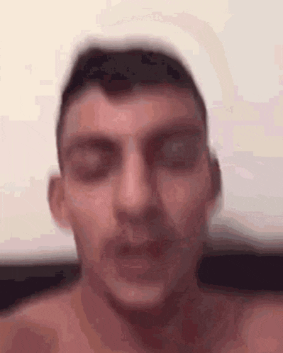 a man without a shirt is looking at the camera .