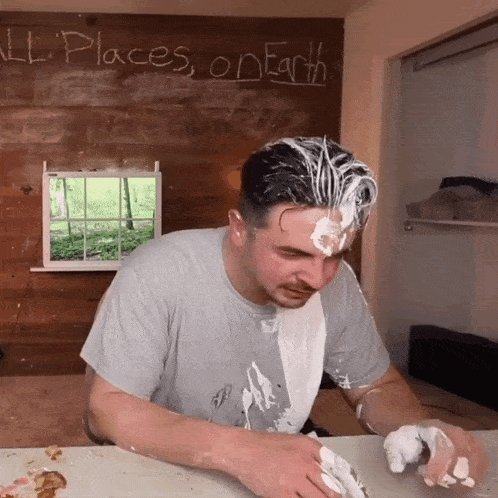 a man with whipped cream on his face is sitting in front of a wall that says " all places on earth "