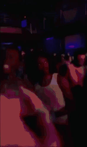 a man with dreadlocks is wearing a white tank top in a crowd of people
