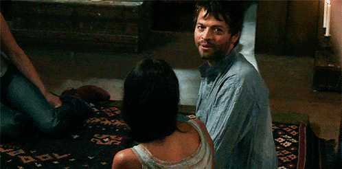 a man is kneeling down next to a woman on a bed in a room .
