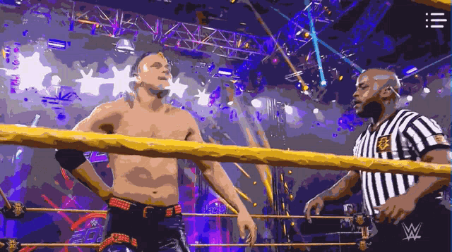 a referee is standing next to a wrestler in a wrestling ring