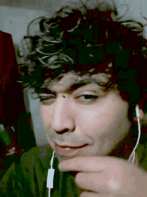 a man with curly hair wearing headphones looks at the camera