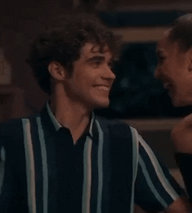 a man and a woman are smiling and looking at each other . the man is wearing a striped shirt .