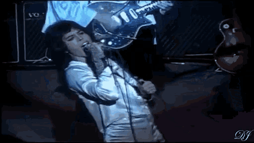 a man is singing into a microphone while playing a guitar on stage .