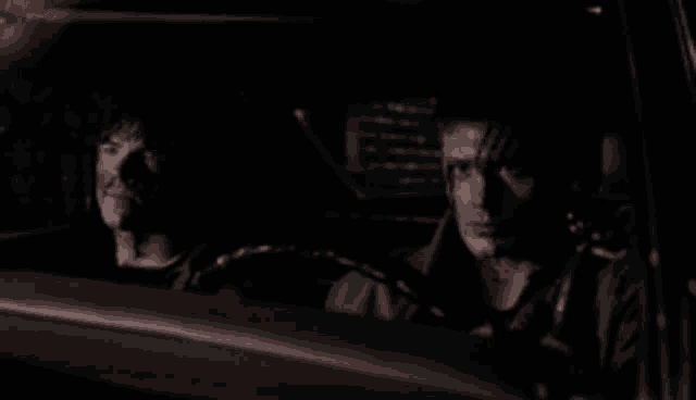 two men are sitting in a car at night .