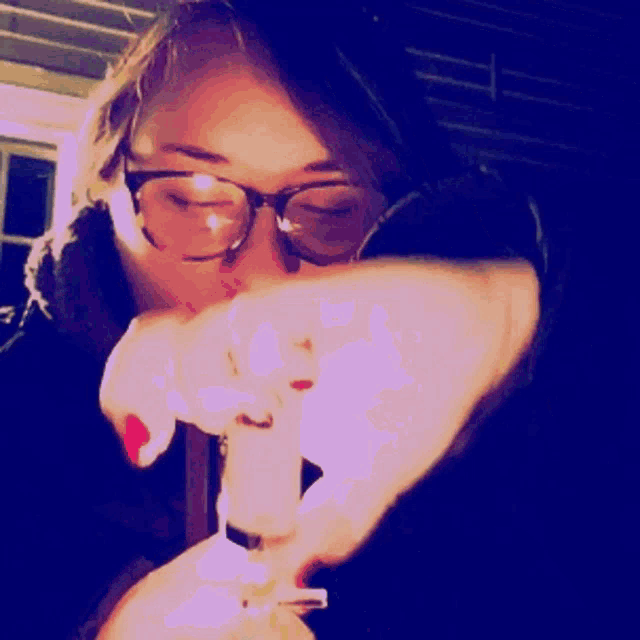 a woman with glasses is lighting a candle
