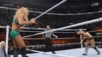 two women are wrestling in a wrestling ring with a referee in the background .