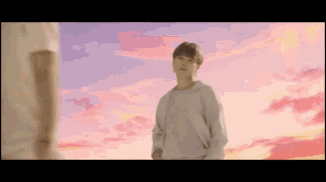 a young man is standing in front of a sunset sky .