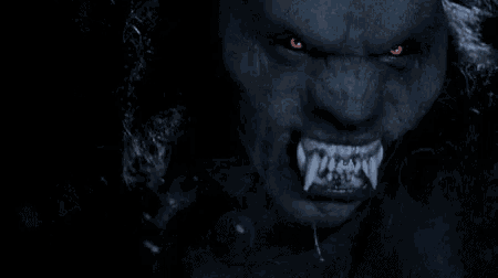 a close up of a werewolf 's face with red eyes .