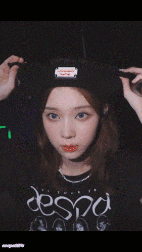 a person holding a microphone in front of their face with a hat that says supreme on it