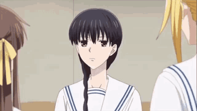 a girl with braided hair is standing next to two other girls in a room .
