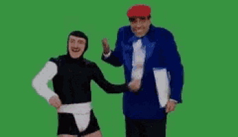 a man in a tuxedo and a man in a black suit are dancing together on a green screen .