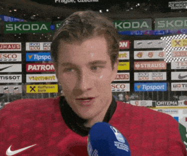 a hockey player talks into a microphone while wearing a red nike jersey