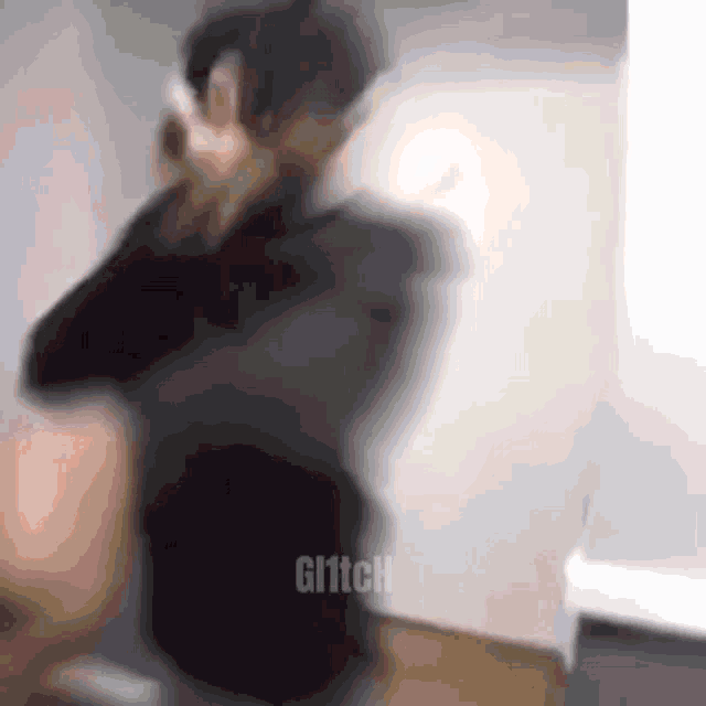 a blurry picture of a man talking on a cell phone in a room .