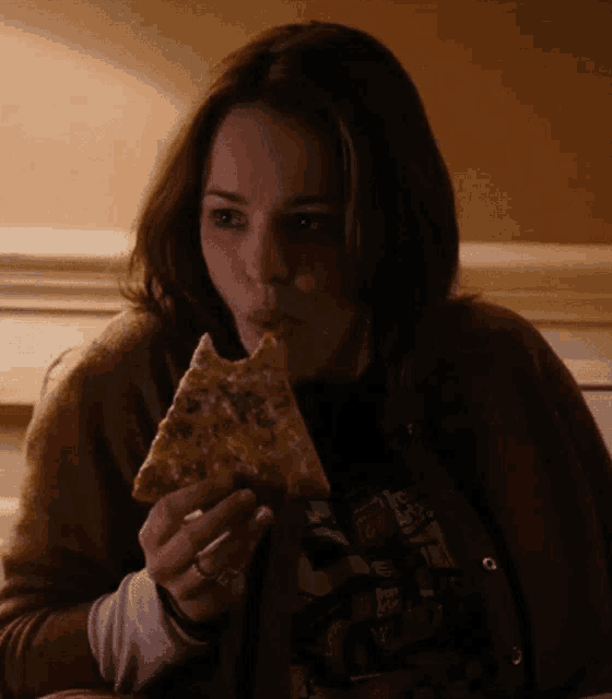 a woman is eating a slice of pizza while wearing a t-shirt that says " i love you "