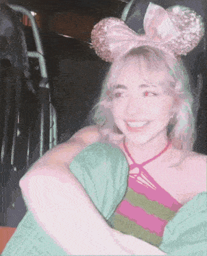 a girl wearing minnie mouse ears and a pink bow on her head