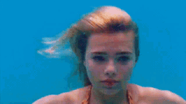 a woman in a bikini is swimming under water