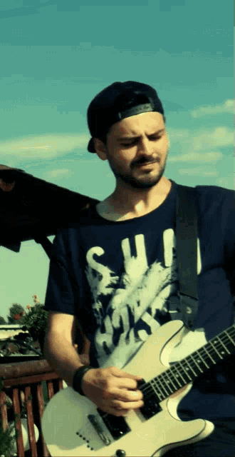 a man in a blue shirt with the word soul on it is playing a guitar