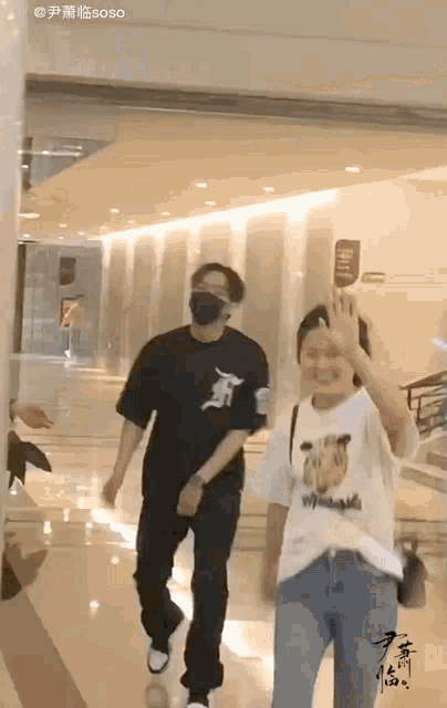 a man wearing a mask is walking with a woman wearing a t-shirt with a zebra on it ..