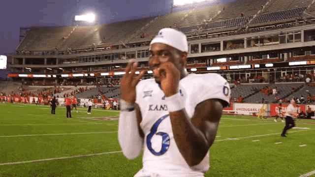 a football player wearing a kani jersey is standing on the field