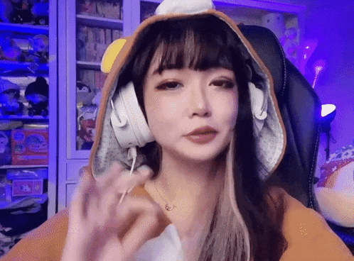 a woman wearing a hoodie and headphones is sitting in a chair in front of a shelf .