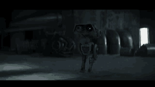 a robot is standing in a dark room with pipes and a light .