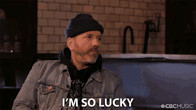 a man wearing a denim jacket and a beanie says " i 'm so lucky "