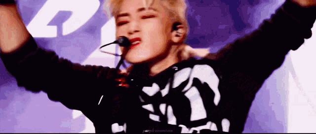 a close up of a person 's face with their arms outstretched and a microphone in their mouth .