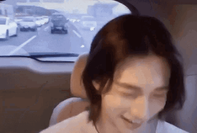 a man is sitting in the back seat of a car with his eyes closed and smiling .