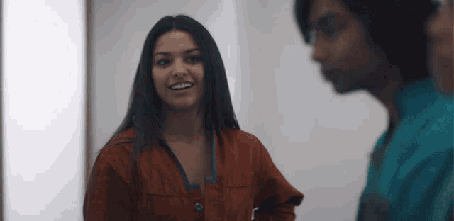 a woman in a red jacket smiles while standing next to a man