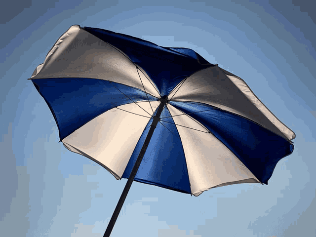 a blue and white umbrella with a blue sky in the background