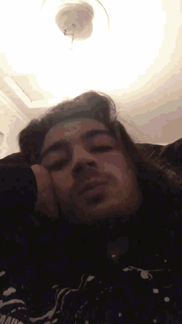 a man with long hair is laying on a couch with his hand on his face