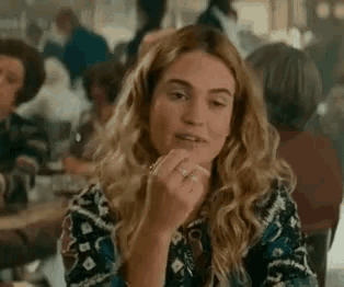 a woman is sitting at a table in a restaurant with her hand on her face .