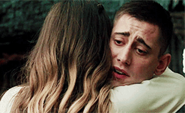 a man and a woman are hugging each other and the woman is crying .